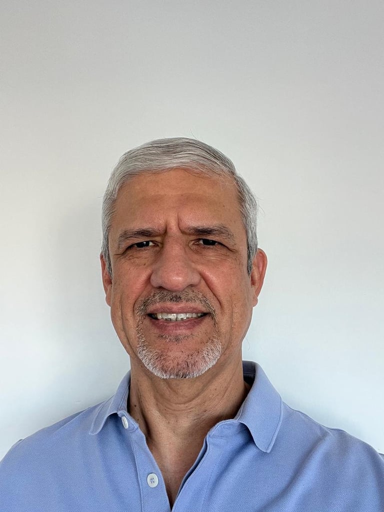 Headshot of René Allamano, middle-aged man with gray hair and beard wearing a light blue button-up shirt